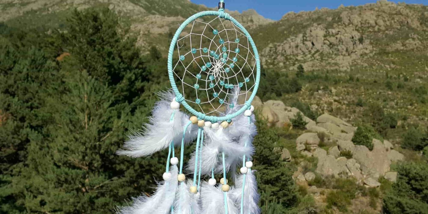 Atrapasueños azul y blanco con montañas al fondocon