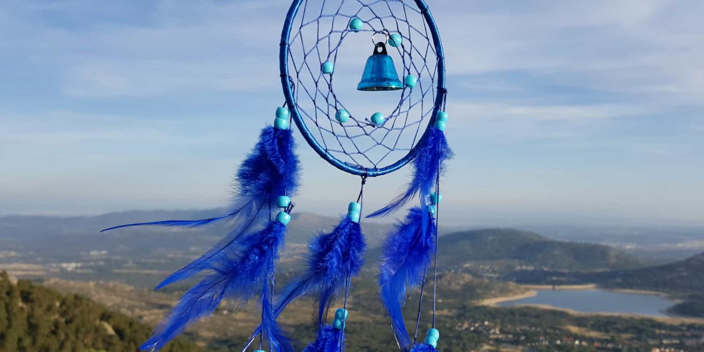 Atrapasueños azul con campanilla y paisaje de fondo
